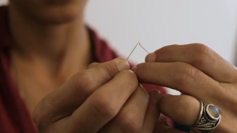 Middle-eastern-woman-trying-to-thread-unsuccessfully-a-red-thread-In-The-eye-Of-A-needle