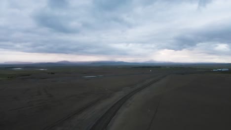Under an overcast sky, a 4K drone captures Iceland&#039;s raw terrain, featuring a stark landing strip with majestic mountains looming in the backdrop
