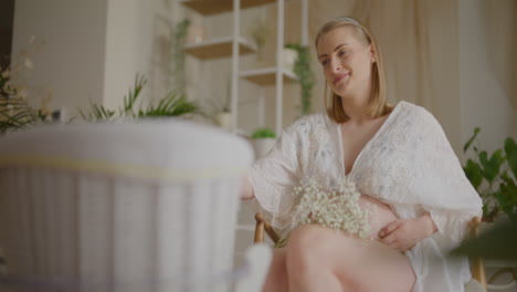 pregnant woman rocking baby in cradle