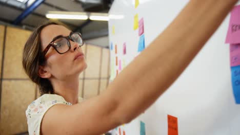 mujer poniendo notas adhesivas en la pizarra