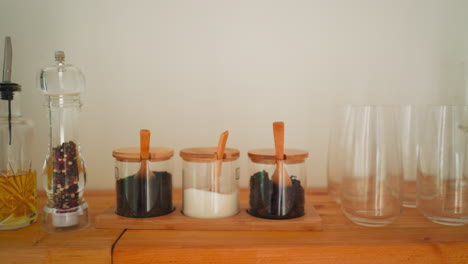 glass jars with spices and tea on a wooden shelf in a kitchen