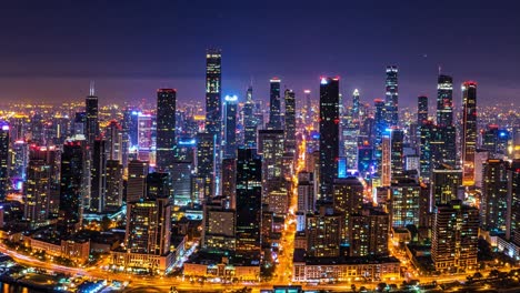a stunning view of a large metropolis illuminated at night, showcasing towering skyscrapers adorned with bright lights. the urban landscape features a blend of modern architecture and busy streets, with vehicles slowly navigating the roads below. the skyline is a dazzling sight, reflecting the energ