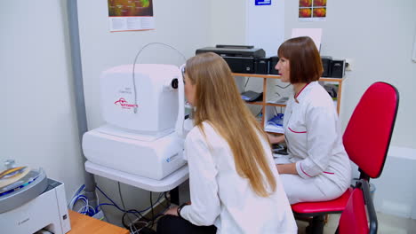 patient checking vision. female optical review of patient eyes with apparatus