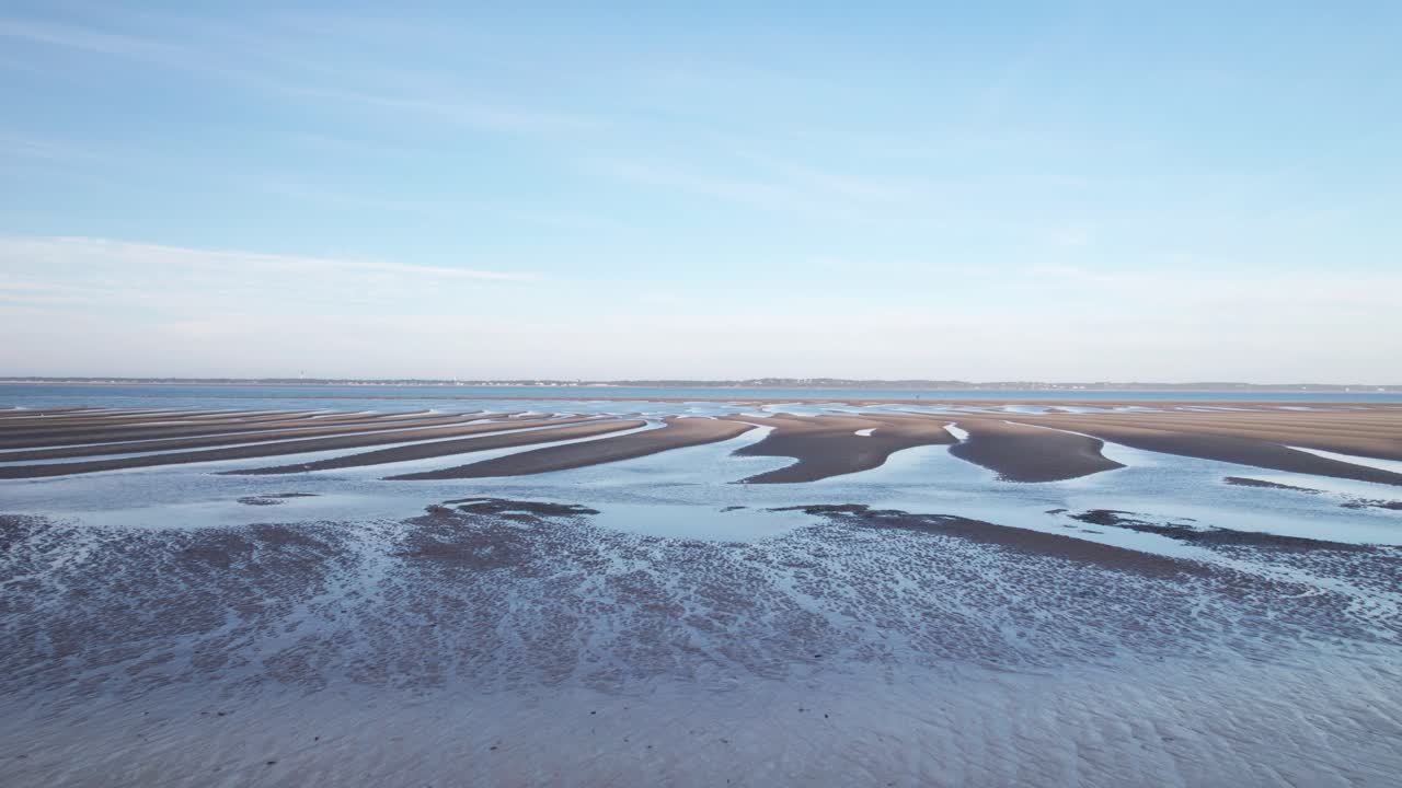 una playa desierta fría con piscinas de agua ondulantes que conducen al océano