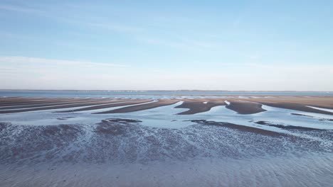 una playa desierta fría con piscinas de agua ondulantes que conducen al océano