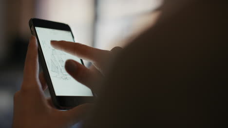 Close-up-of-womans-hands-using-smart-phone-technology-to-read-architectural-plans