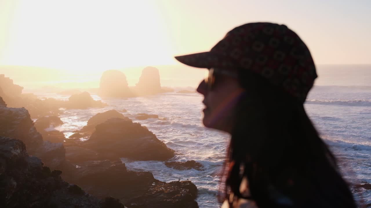 mulher de costas assistindo o pôr do sol com o sol no mar na praia de surf em punta de lobos