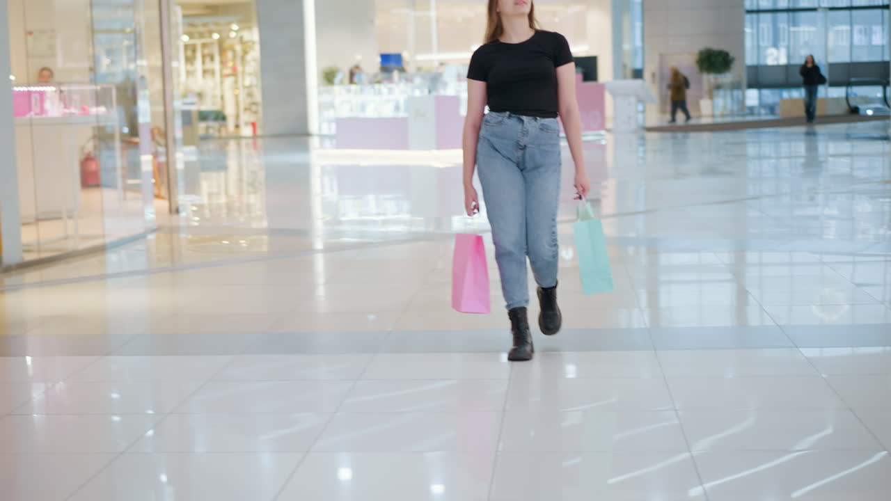 estudiante sosteniendo bolsas de compras en un vibrante centro comercial, girándose y mirando a su alrededor con curiosidad mientras camina, con otros compradores pasando, mostrando la atmósfera de un centro comercial ocupado