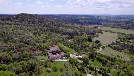 the house stands amidst a dense forest, with the blue sky adorned by white fluffy clouds