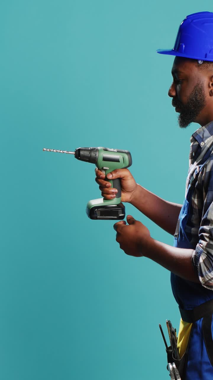 Vertical video: Male builder using power drill instrument on wall