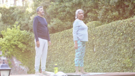 Focused-diverse-senior-couple-practicing-yoga-in-garden