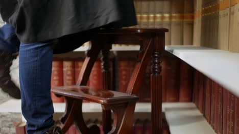 a student climbing library ladders steps to reach books on a high shelf in a judges law library