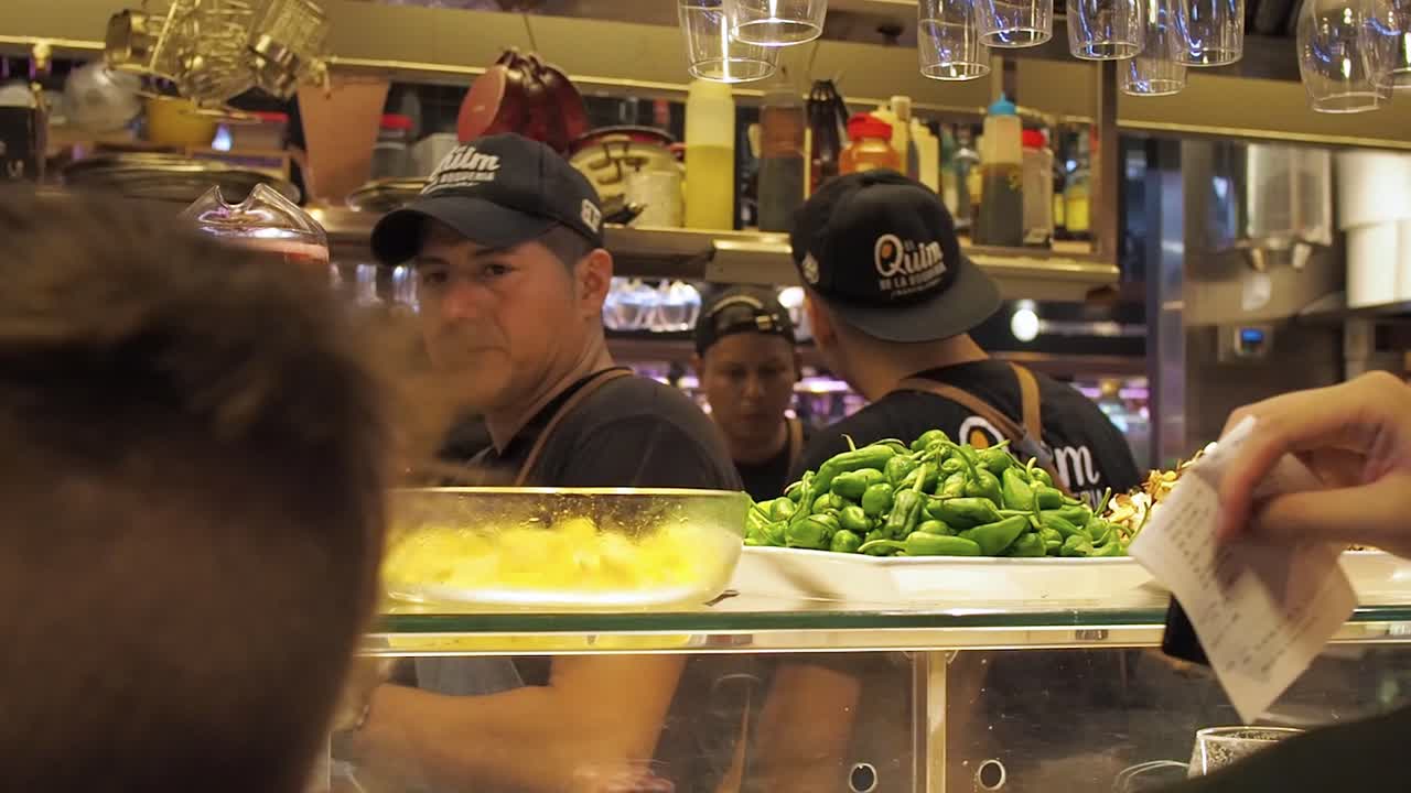 a man delivers ticket at the restaurant El Quim de la Boqueria in traditional market in Barcelona, La Boqueria