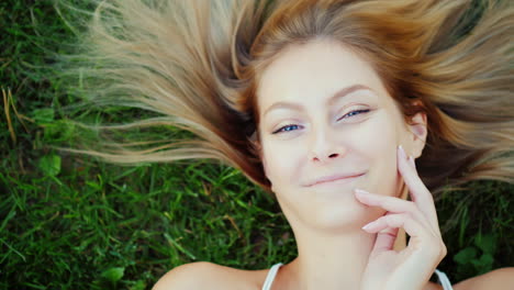 portrait of a young woman with long hair she lies on the lawn his hair lies beautifully on the grass