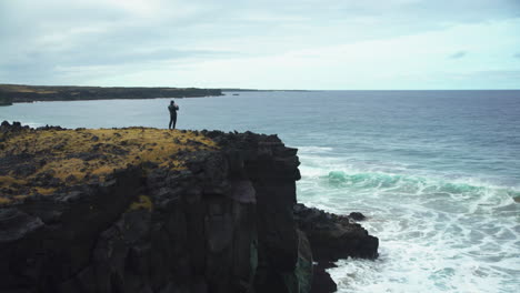 Weitwinkelaufnahme-Eines-Mannes,-Der-Wellen-Von-Einer-Klippe-In-Island-Aus-Fotografiert