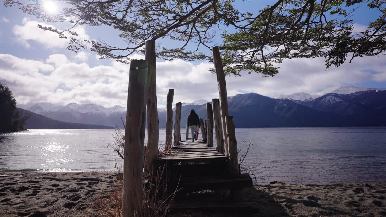 Mother and daughter walking on a rustic wooden and peaceful pier at Lago Traful, Argentina