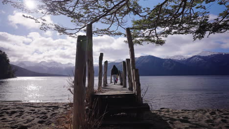 mother and daughter walking on a rustic wooden and peaceful pier at lago traful, argentina