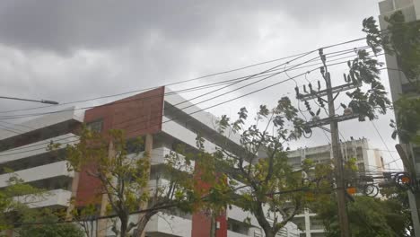 Stormy-Weather-Looking-Up-at-Gray-Clouds-with-a-Building-in-the-Foreground,-Thailand