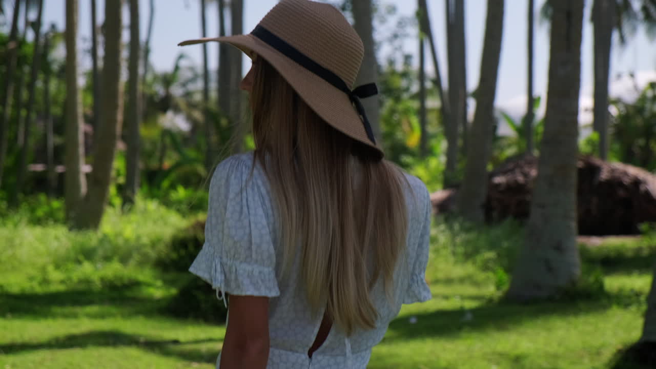 Woman in a straw hat relaxing in a tropical garden
