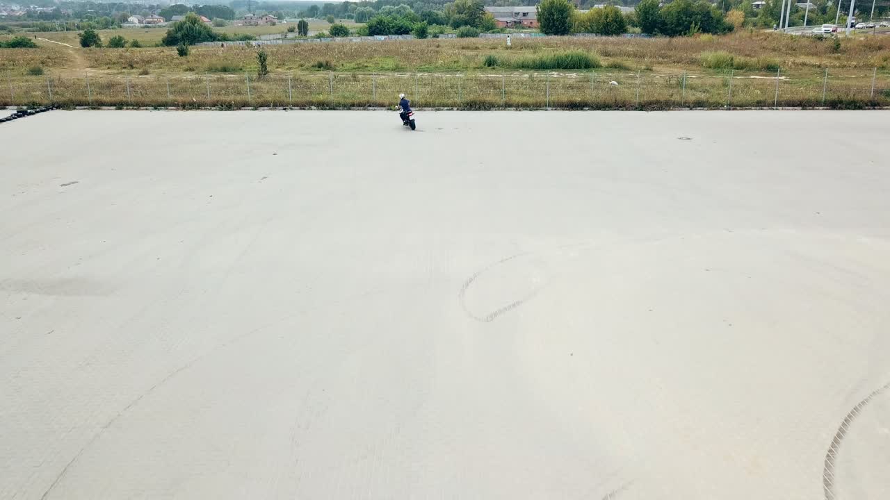 Rider making stunt on motorbike. Aerial view of young man riding motorcycle on asphalt road