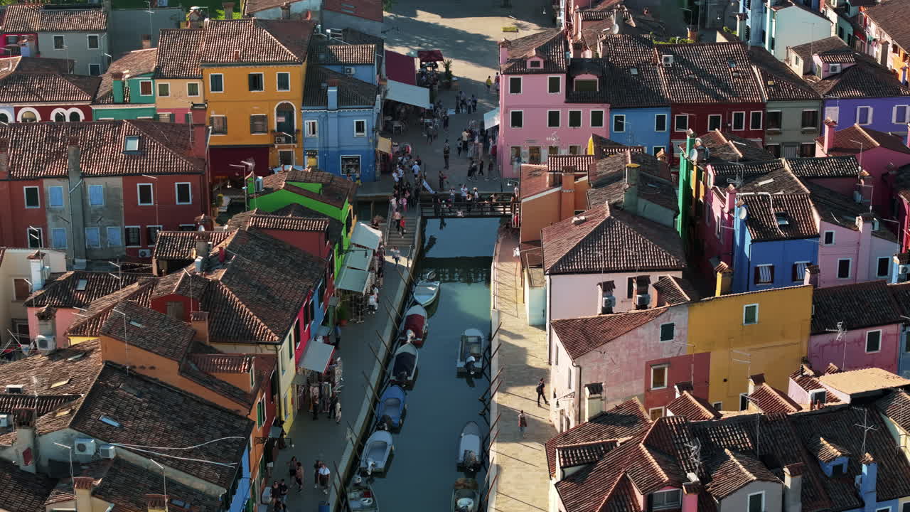 Aerial drone view of boats on the sides of a canal near the colourful houses of Burano island, Italy