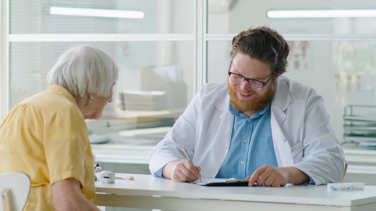 Male Doctor Consulting Elderly Woman in Medical Office