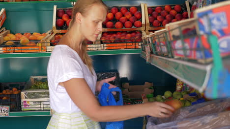 una mujer joven eligiendo peras en una tienda de frutas.