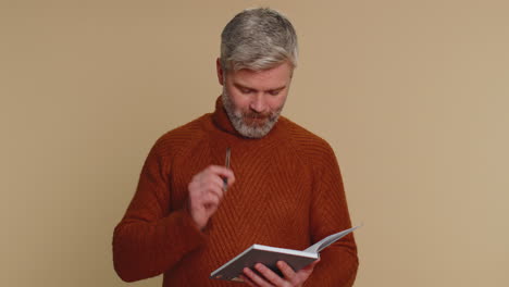 thoughtful journalist man making notes, writing down thoughts with pen into notepad notebook diary