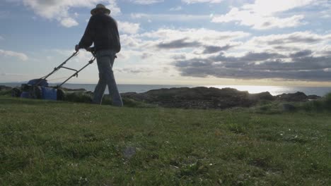 A-Man-With-A-Self-Propelled-Trimmer-Cuts-Grass-In-A-Lawn-Near-The-Sea-2