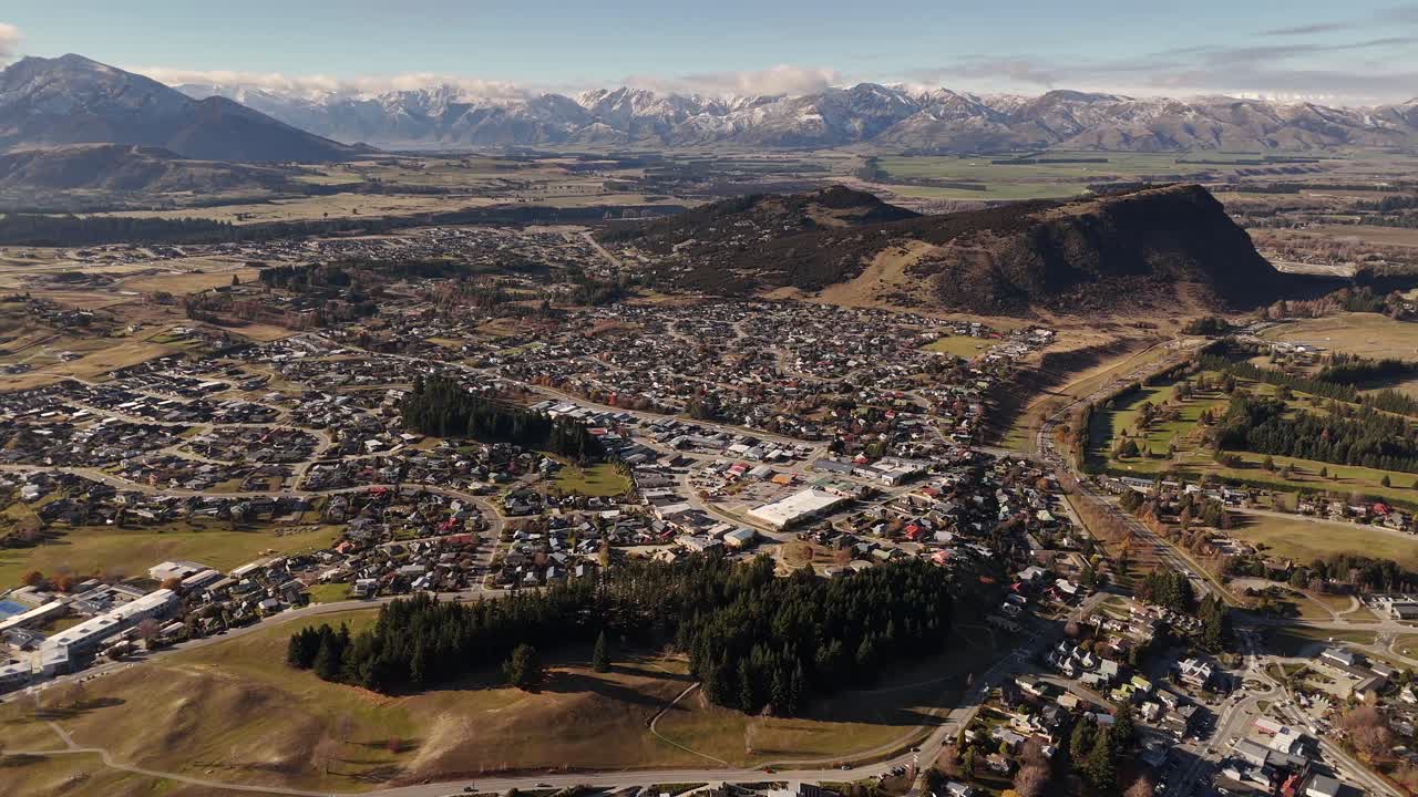 Aerial of Wanaka Town on the South Island of New Zealand during a sunny day showing the town layout, Lake Wanaka and surrounding mountains