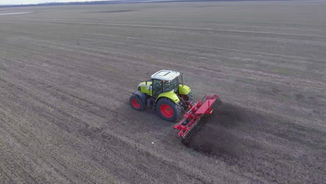 video de seguimiento aéreo: el tractor procesa el suelo en el campo se mueve a lo largo de la diagonal del marco