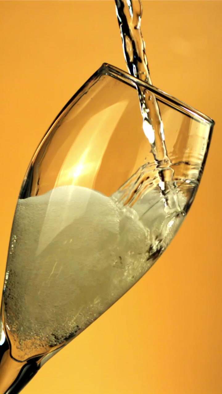Versamento di Champagne in un flûte con bollicine su sfondo dorato