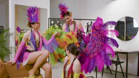 bellas bailarinas divirtiéndose, hablando y preparándose con vestidos de plumas