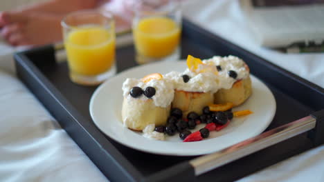 room service pancakes and orange juice on the edge of a bed in a hotel room