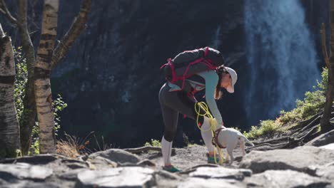 una excursionista acaricia a un pequeño terrier blanco