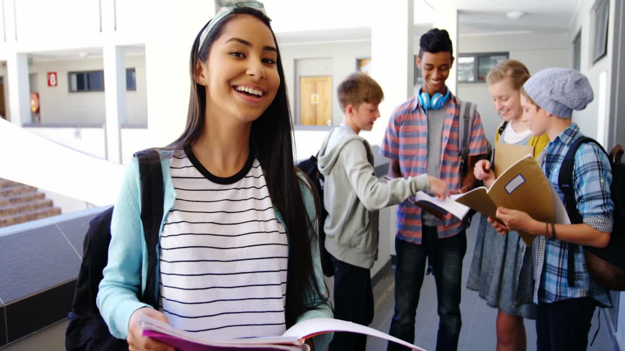 niña de escuela de pie en el pasillo con un cuaderno