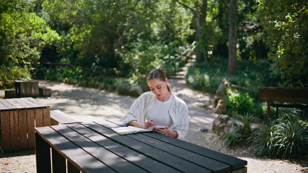 매력적인 프리랜서 노트 패드와 함께 작업하는 숲 테이블. 온라인 서핑 여인