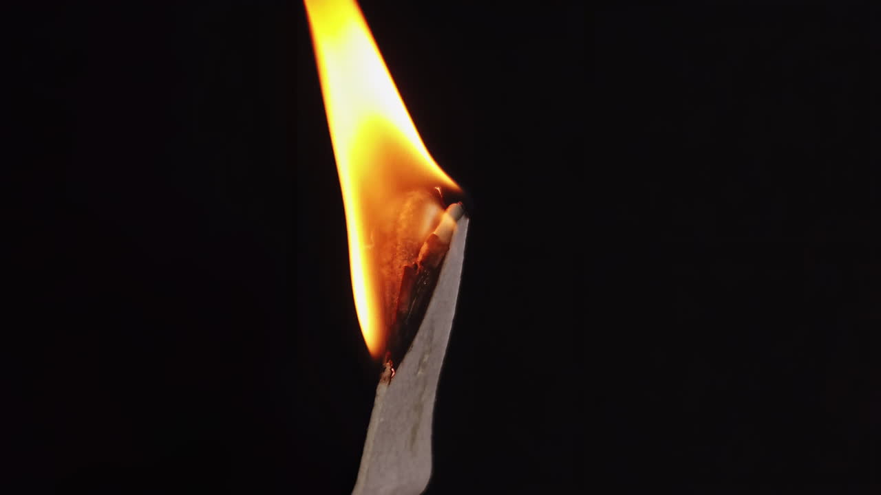 Wax on the stick burning in front of a black background. Ecology idea. Close up. Slow motion shot