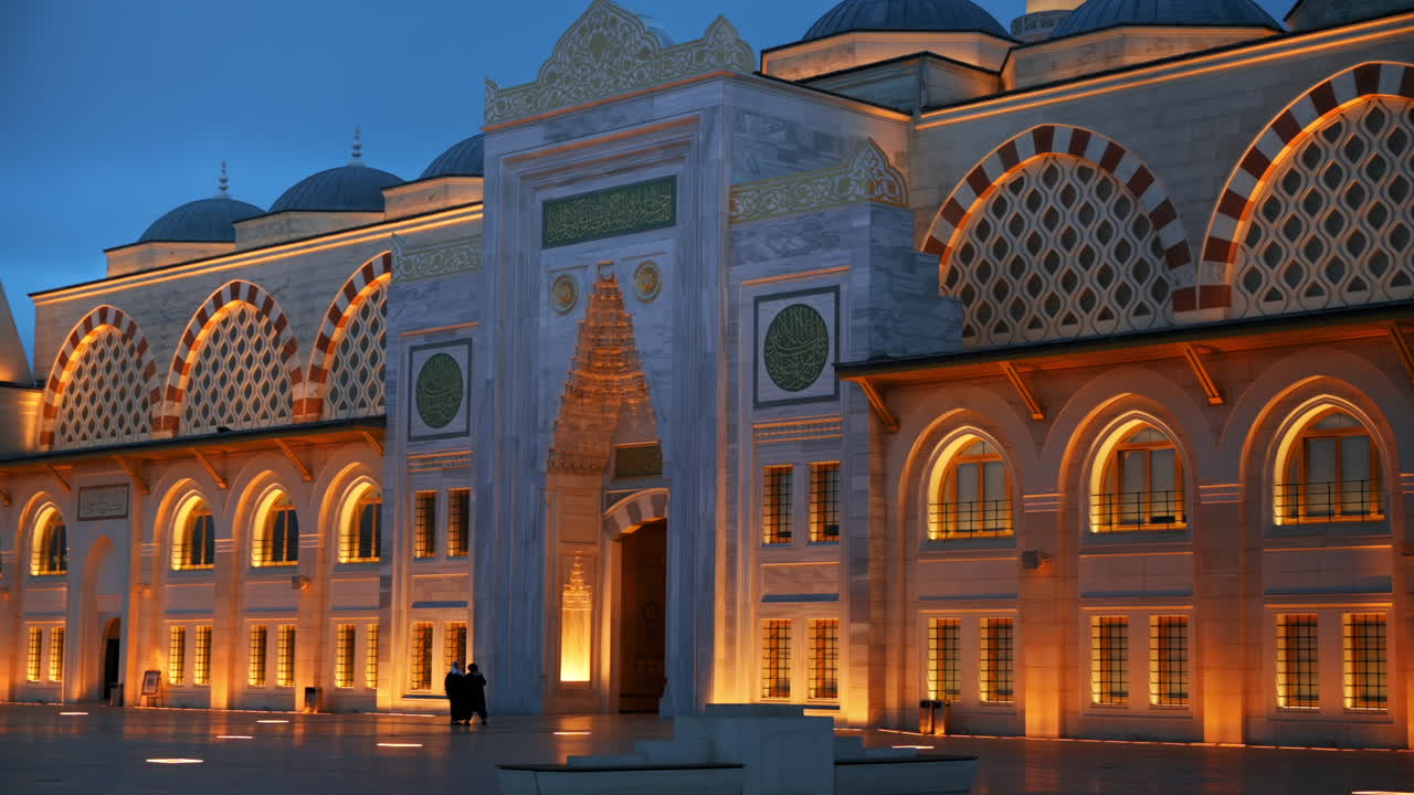 View of the Camlica Mosque in Istanbul at evening, Turkey. Facade made of white stone, illumination, few people in front of it
