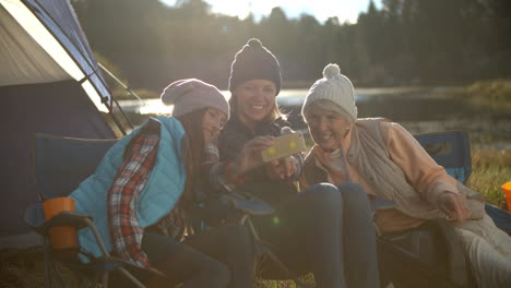 Mother,-daughter-and-grandmother-taking-selfie-outside-tent