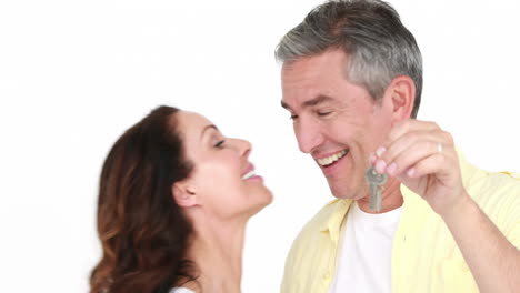 una pareja feliz y atractiva con la llave de una casa nueva.