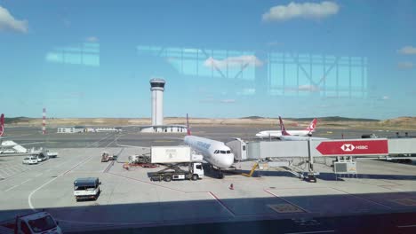 in partly cloudy daylight, ground services load a parked turkish airlines aircraft on the apron of istanbul airport