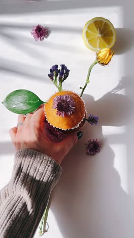 woman holding a decorated cupcake with flowers