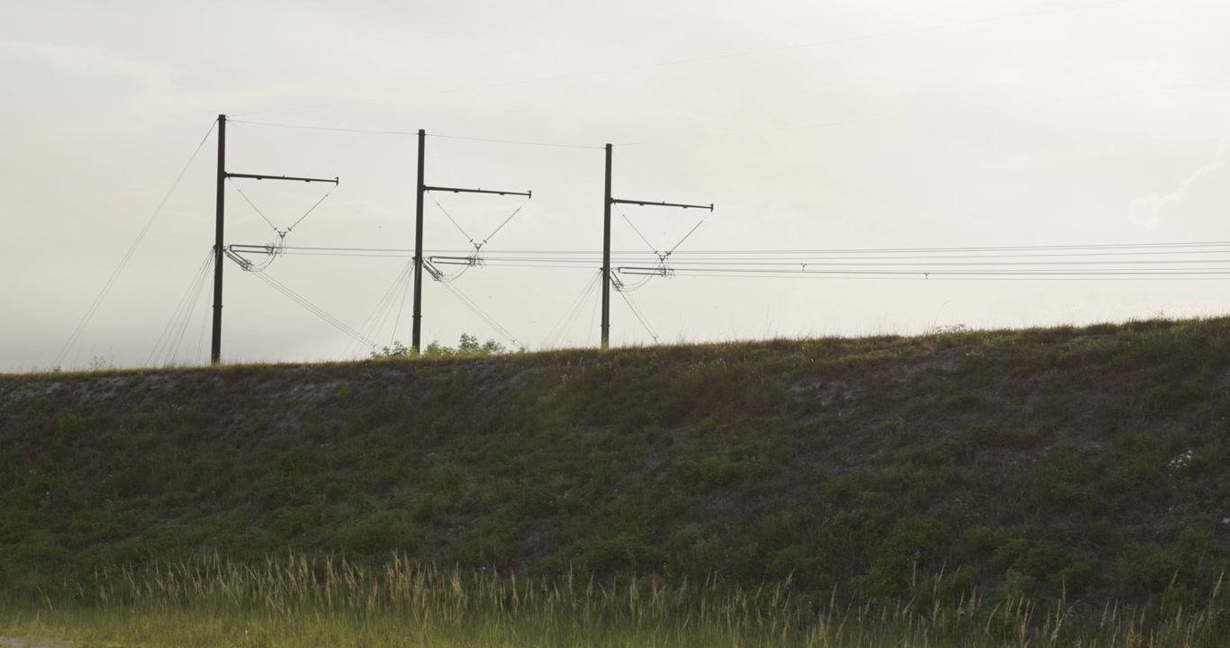 4K handheld shot of high-voltage transmission towers and power lines near the Florida Everglades. The levee stretches across the foreground