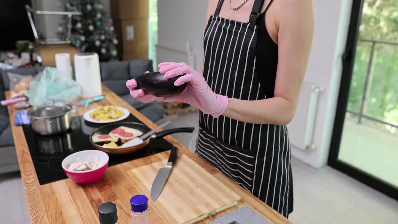 Person holding an eggplant in the kitchen