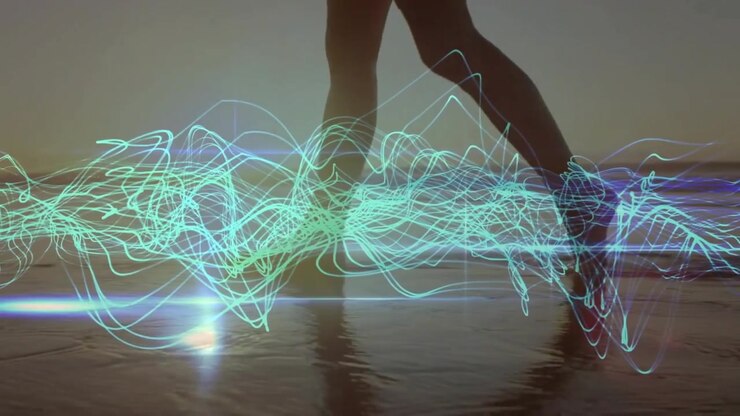 Mid-adult woman stepping into water causing technology teal blue waveforms syncing to footfalls