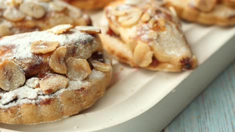 close-up of a plate of delicious pastries topped with almonds and powdered sugar