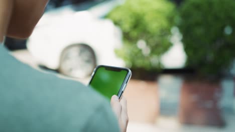 Handheld-Ansicht-Eines-Mannes,-Der-In-Der-Stadt-Ein-Greenscreen-Handy-Benutzt