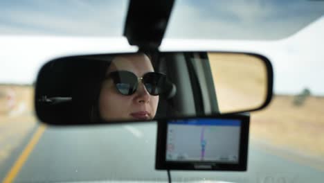 a woman - filmed through the rearview mirror - driving through the desert in namibia