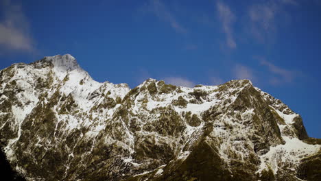 Zeitraffer-Schneebedeckte-Berggipfel,-Während-Weiße-Wolken-über-Einen-Blauen-Himmel-Geblasen-Werden